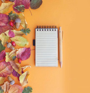 Kahverengi zemin üzerinde sonbahar yaprakları olan boş defter