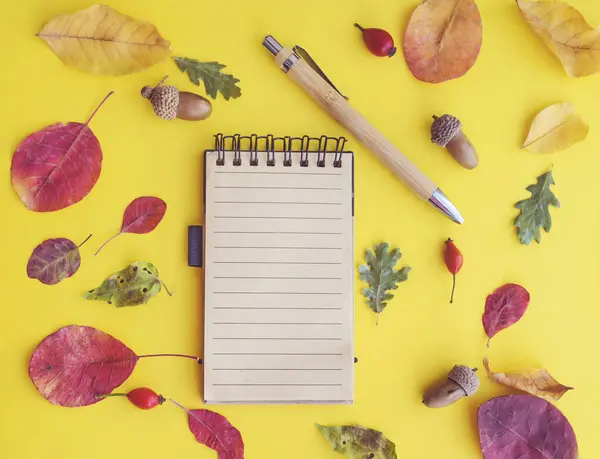 Kahverengi zemin üzerinde sonbahar yaprakları olan boş defter