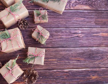 Ekonomi kağıdında kırmızı kurdeleli hediye kutuları. Ahşap arka planda Noel hediyeleri.