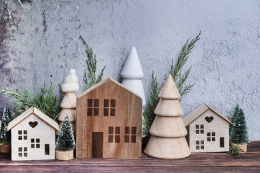 Noel odasının iç dekorasyonu İskandinav tarzında ahşap küçük evler ve çam ağaçlarıyla süslenmiş.