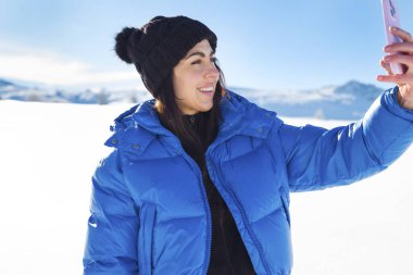 Winter Mountain 'da cep telefonu kullanan genç bir kadın.