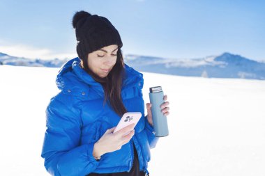 Winter Mountain 'da cep telefonu kullanan genç bir kadın.