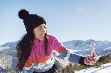 Kışın Karlı Dağ 'da cep telefonu kullanan güzel kadın. Mutlu kadın selfie çekiyor.