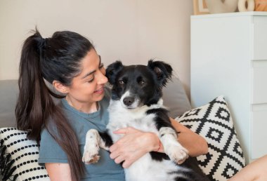 Evlatlık alınmış siyah köpeğini kucaklayan bir kadın.