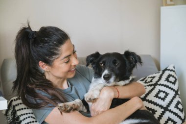 Evlatlık alınmış siyah köpeğini kucaklayan bir kadın.