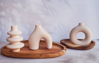 Ahşap tepside modern bej seramik küçük vazolar. İskandinav iç mimarisi