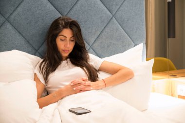 Güzel kadın uyumadan önce akıllı telefon kullanıyor.