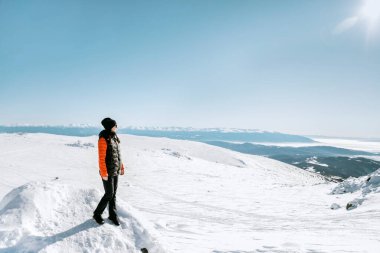 Kışın karlı dağda bir taşın üzerinde oturan kadın.