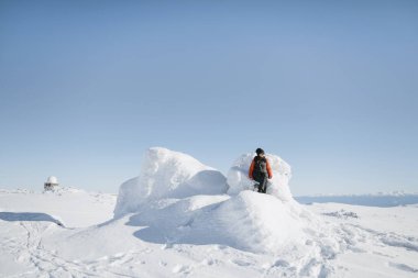 Kışın karlı dağda bir taşın üzerinde oturan kadın.