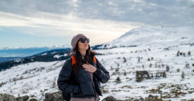 Karlı bir dağda temiz hava soluyan rahat bir kadın.