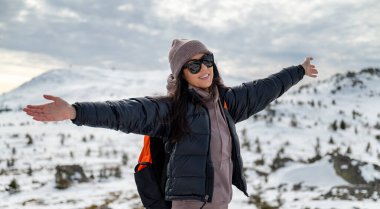 Kışın karlı dağda kollarını açmış gezgin kadın. 
