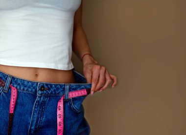 Kot pantolon giyen ve kilosunu ölçen bir kadın.