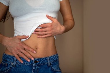 Dar karnını gösteren kot pantolonlu bir kadın. 