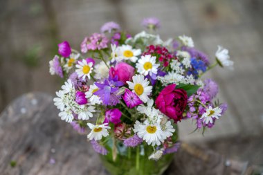 Güzel bir buket yaz çiçeğiyle ahşap bir bankta cam vazo