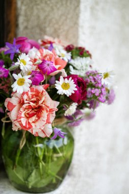 Güzel bir buket yaz çiçeğiyle ahşap bir bankta cam vazo