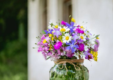 Güzel bir buket yaz çiçeğiyle ahşap bir bankta cam vazo