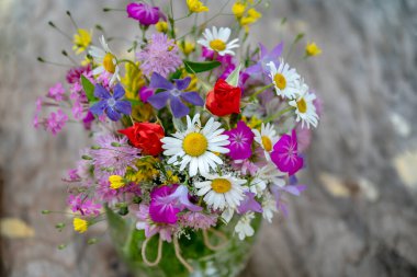 Güzel bir buket yaz çiçeğiyle ahşap bir bankta cam vazo