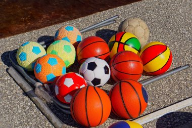 Beton oyun sahasında farklı sporlar için renkli top koleksiyonu