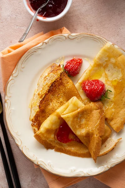 Overhead view of french crepes with berries food on plate pink surface