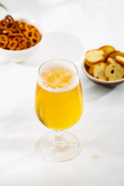 A glass light beer and snacks in bowl food and drink