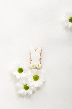 Easter sugar bunny and white flowers holiday concept top view