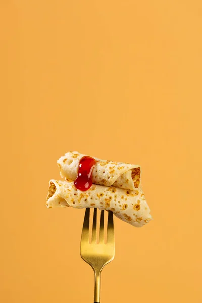 stock image Two slices of thin crepes on a golden fork food background strawberry jam