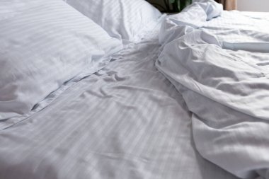 Yatak odası dağınık, bembeyaz, saten bir yatak odası.