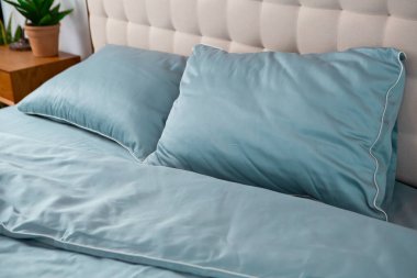 Kırışık mavi pamuklu yatak örtüsü ve yastıklar.