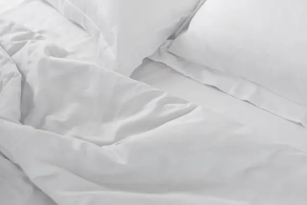 白色缎子在未做的床上压皱了床单 免版税图库图片
