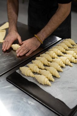 Pişmemiş kruvasanları fırın konseptine hazırlayan eller.