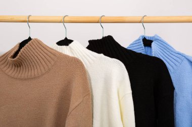 Yarı sezon yün kazaklar ve yakalı ahşap elbise askıları.