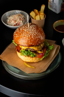 Peynirli ve patatesli hamburgeri siyah masaya koy.