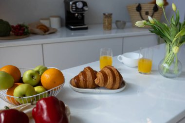 Beyaz mutfak ve kahvaltı meyveli kruvasan masa sabah rutin konsept modern ev.