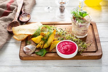 Tuzlu ringa balığı ve ahşap tahtada yaban turpu soslu kızarmış patates dilimleri.