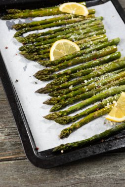 Fırın tepsisinde limon ve sert peynirli ızgara yeşil kuşkonmaz.