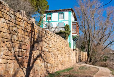 Resimli bir evi olan bir kerpiç ve taş duvar.