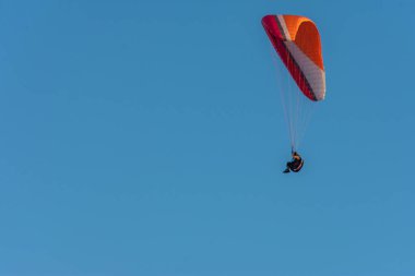 Mavi gökyüzü ile uçan renkli bir paraglider.