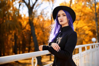 Sonbaharda parkta mor saçlı bir kız.