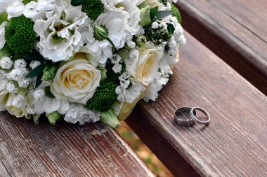 Arka planda alyans ve buket var.