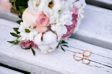 Arka planda alyans ve buket var.