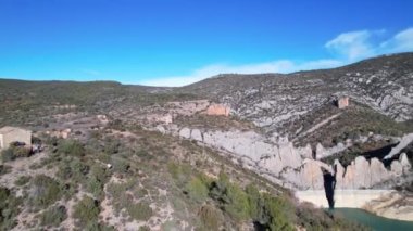 Panorama hava aracı, San Marcos şapeli yakınlarındaki terk edilmiş Canyelles rezervuar turkuaz gölü kenarındaki terk edilmiş Finestres köyünde Katalonya ve Aragon arasındaki sınırda turistleri vurdu. İspanya. 4K