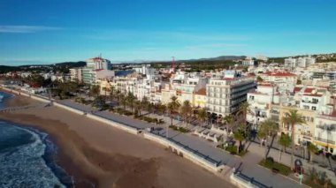 İHA, sahil boyunca Sitges 'deki palmiye ağaçlarıyla çevrili güzel plajlarda uçuyor. Akdeniz manzaralı plaj ve oteller. Yumuşak deniz dalgaları sessizce kıyıya vurur. Film tanıtımı. 4K video