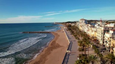 İHA, sahil boyunca Sitges 'deki palmiye ağaçlarıyla çevrili güzel plajlarda uçuyor. Akdeniz manzaralı plaj ve oteller. Yumuşak deniz dalgaları sessizce kıyıya vurur. Film tanıtımı. 4K video