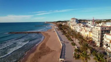 İHA, sahil boyunca Sitges 'deki palmiye ağaçlarıyla çevrili güzel plajlarda uçuyor. Akdeniz manzaralı plaj ve oteller. Yumuşak deniz dalgaları sessizce kıyıya vurur. Film tanıtımı. 4K video