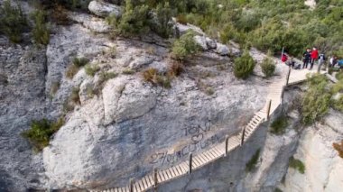 İspanya, Pireneler 'deki Congost de Montrebei vadisindeki yürüyüş yolunun bir parçası olarak kayalıklardaki ahşap merdivenlerin panoramik ve etkileyici hava manzarası. Turistler dağda dinlenir. 4K video
