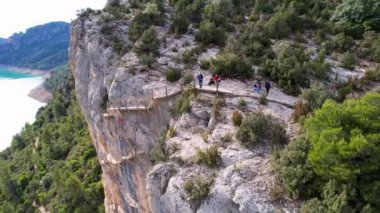 Congost de Montrebei vadisindeki yürüyüş yolunun bir parçası olarak Katalonya, Pireneler, İspanya 'daki nehirde bitki örtüsüyle çevrili, kayalıklardaki ahşap merdivenlerin panoramik ve güzel hava manzarası. 4K 