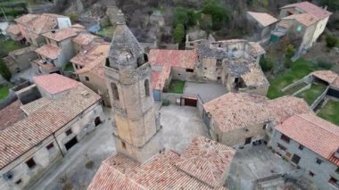 Eski ortaçağ geleneksel mimari köyü Luzas 'ın panoramik insansız hava aracı görüntüsü ve San Cristobal' ın Roma kilisesinin kilise çan kulesi. Huesca ili, Aragon, İspanya. 4K video