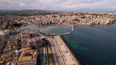 Syracuse, İtalya 'da insansız hava aracı keşiflerine çıkın, şehirlerin ikonik mirasını ve cennet kıyı şeritlerini sergileyin. Parlak yatlar, güneşli denizde sürükleniyor. Lüks ve sükunetin büyüleyici bir sahnesini oluşturuyor.