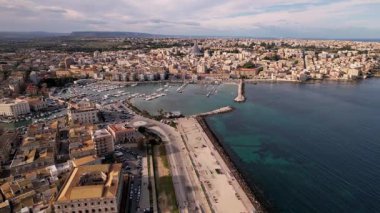 Tarihin gök mavisi dalgalarıyla buluştuğu İtalya 'nın Syracuse kentinin nefes kesici hava manzarası. Şahit büyüleyici şehir manzarası resimli kıyı şeridiyle uyumlu bir şekilde harmanlanıyor. Zarif yatlar pırıl pırıl denizler