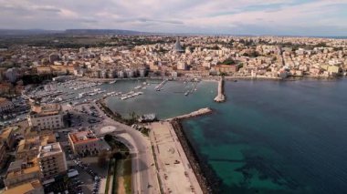 İtalya 'nın Syracuse kentindeki çarpıcı drone panoramasını keşfedin. Antik mimari ve manzaralı kıyı şeritleri hayal gücünü cezbediyor. Görkemli yatlar berrak mavi suları süsler, şehirleri güzelleştirir.